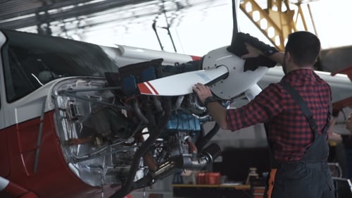 Mann reinigt Flugzeugpropeller im Hangar