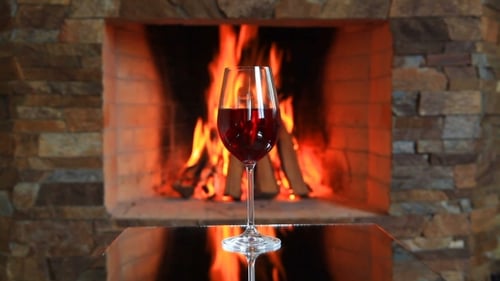 Wineglass with Red Wine Near a Fireplace