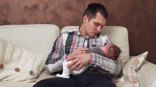 Father Holding Newborn Baby in Cozy Home Setting