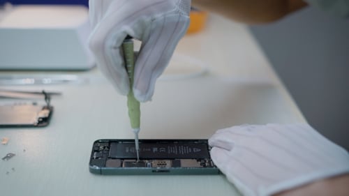 Der Elektronikingenieur verdreht nach einer unabhängigen Telefonuntersuchung Schrauben in einem Smartphone