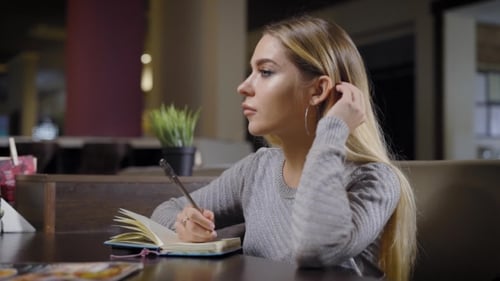 Beautiful Smart Woman Is Spending Time in Cafe Writing