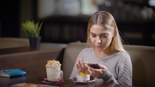 Cute Young Girl Is Having a Break in a Cafe