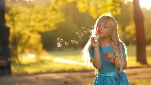 Girl Blowing Bubbles in a Sunny Park