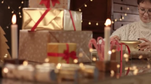Woman Wrapping Christmas Gifts with Ribbon