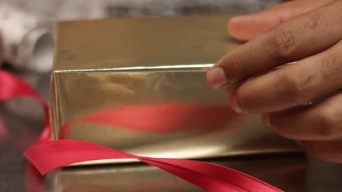 Decorating Gold Wrapped Gift With Merry Xmas Sticker