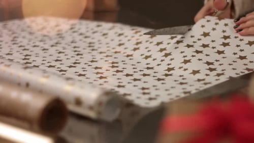 Woman Cutting Christmas Wrapping Paper on Glass Table