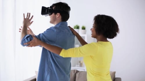 Man Wearing VR Headset With Woman Guiding