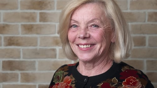 Woman Smiling in Front of a Brick Wall
