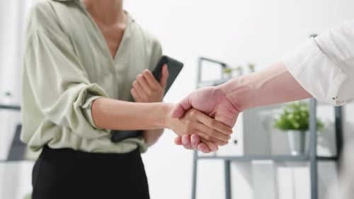 Creative people in casual wear discussing business shaking hands together while standing in office