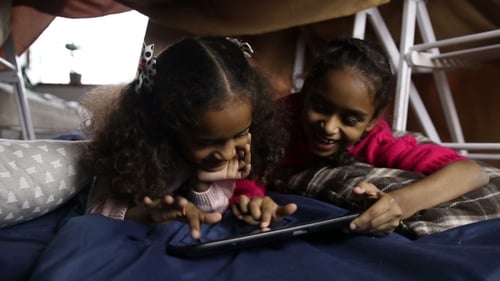 Girls Laughing Together Playing on Tablet Inside Fort