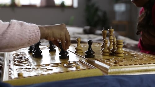 Close Up of People Playing Chess on Carved Board