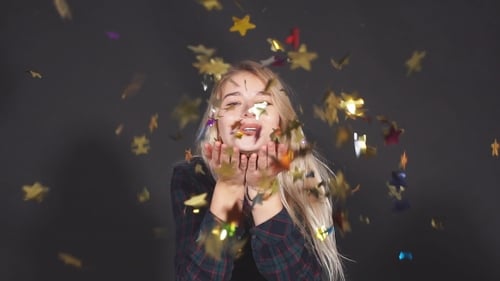 Woman Blowing Confetti with a Cheerful Smile