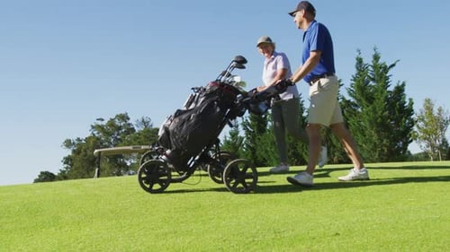 Caucasian senior couple walking with their golf bags at golf course on a bright sunny day