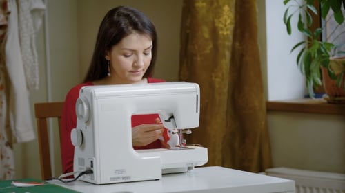 A Woman Works for a Sewing Machine in a Home Studio, a Lady Makes Clothes, She Handles Creativity