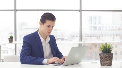 Young Businessman Working at Laptop in Office.