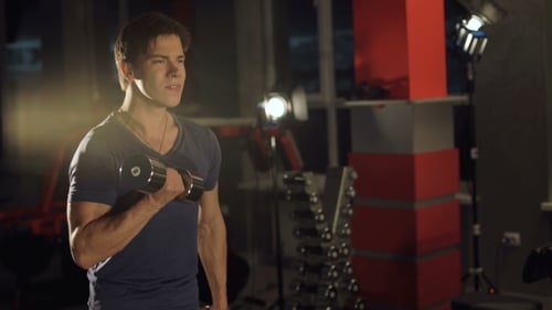 Young Man Hardly Lifting Dumbbells in the Gym