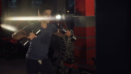 Young Sweaty Man Hardly Lifting Dumbbells in the Gym.