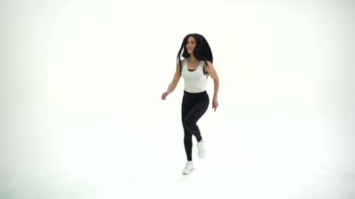 Athletic Young Beautiful Woman Brunette with Long Hair Warming Exercises in Studio on a White