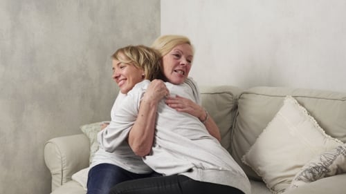 Woman Huddles with Friend on Couch