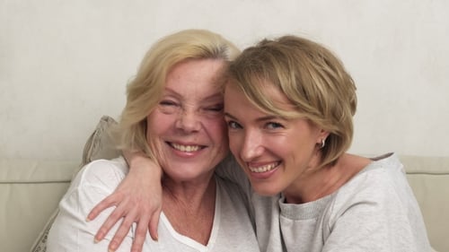 Senior Woman and Young Adult Daughter Embracing Indoors