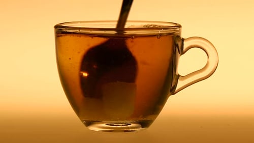 Stirring Sugar into Amber Colored Drink with Spoon