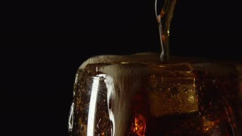 Soda being poured into glass with ice