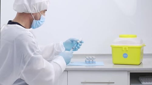 Crop doctor filling syringe with drug in hospital