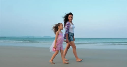 Young Family, Mother and Daughter Are Walking Along the Coast. Happy Family Walking on Sea Coast.