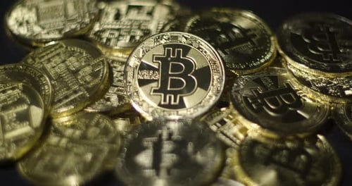 Echte goldene Münzen mit Bitcoin-Logo auf schwarzem Hintergrund