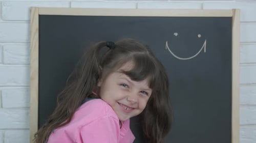Smiling Young Child in Front of Chalkboard