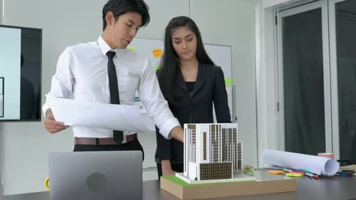 Architects Reviewing Building Plans and Model in Office