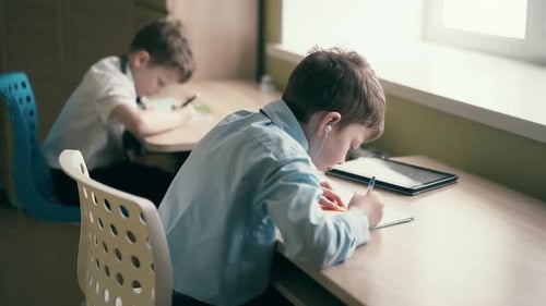 Two Children Studying at Desks in Sunny Room