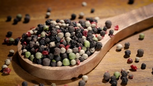 Mixed peppercorns in wooden spoon close up shot