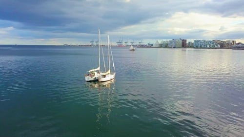 Sailboats Floating on Calm Water Near Urban Shore