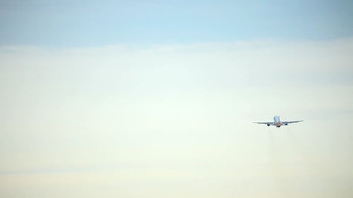Airplane Flying Away in a Cloudy Sky