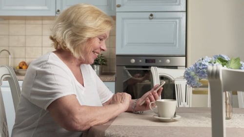 Senior Woman Using Phone in Bright Kitchen