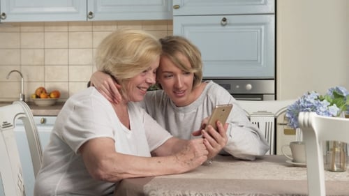 Blonde Woman and Senior Woman Use Smartphone
