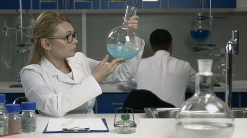 Female Scientist Examining Flask with Blue Liquid