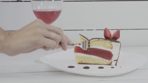 Fork Cutting Strawberry Cake with Red Wine