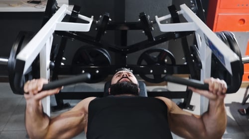 Strong Man Is Pumping Muscles at the Gym, Strength Exercises on Simulators, Athlete at Fitness Club
