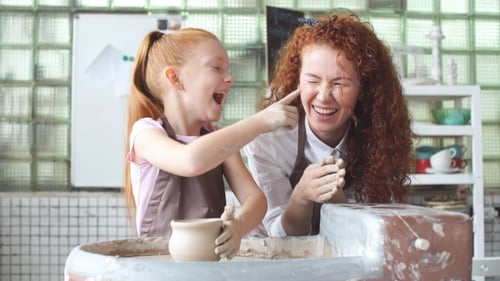 Girl Learning Pottery from Woman in Bright Studio