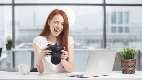 Young Woman Holding Camera and Smiling in Office