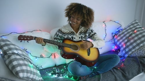 Young Woman Plays Guitar at Home at Christmas