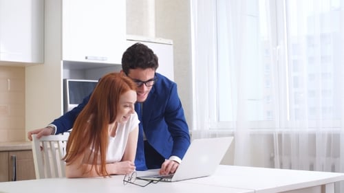 Young Couple Smiling at Laptop in Kitchen