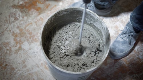 Drill Mixing Concrete in a Grey Bucket