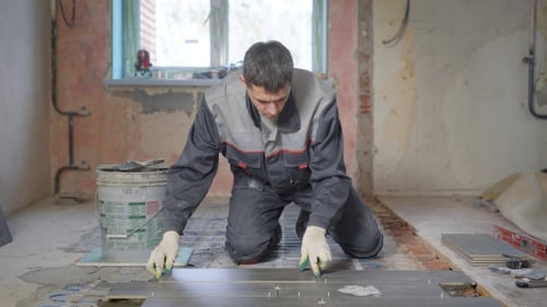 Young Adult Tiling Floor in Home Renovation Project