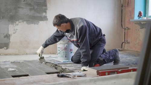 Man Laying Floor Tile in Home Renovation