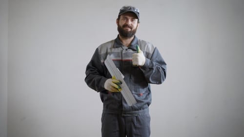 Happy Builder Is Standing By the Wall with a Spatula in a Flat
