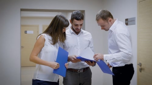 De jeunes avocats demandent l'aide d'un homme qui marche dans le couloir, les employés de l'agence juridique
