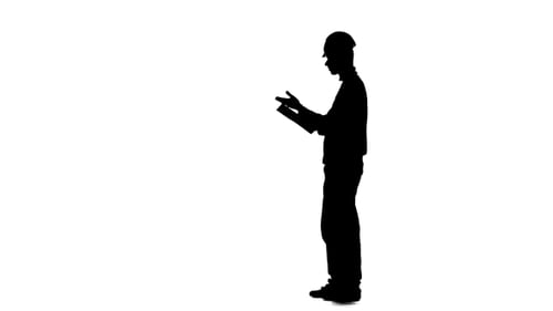 Builder Looks at the Paper Plan of the Building. Silhouette. White Background